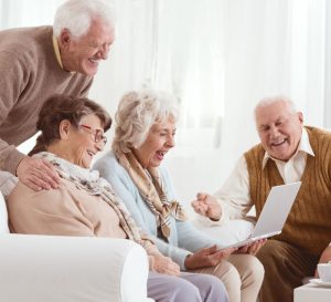Senior friends watching old photos together on a laptop